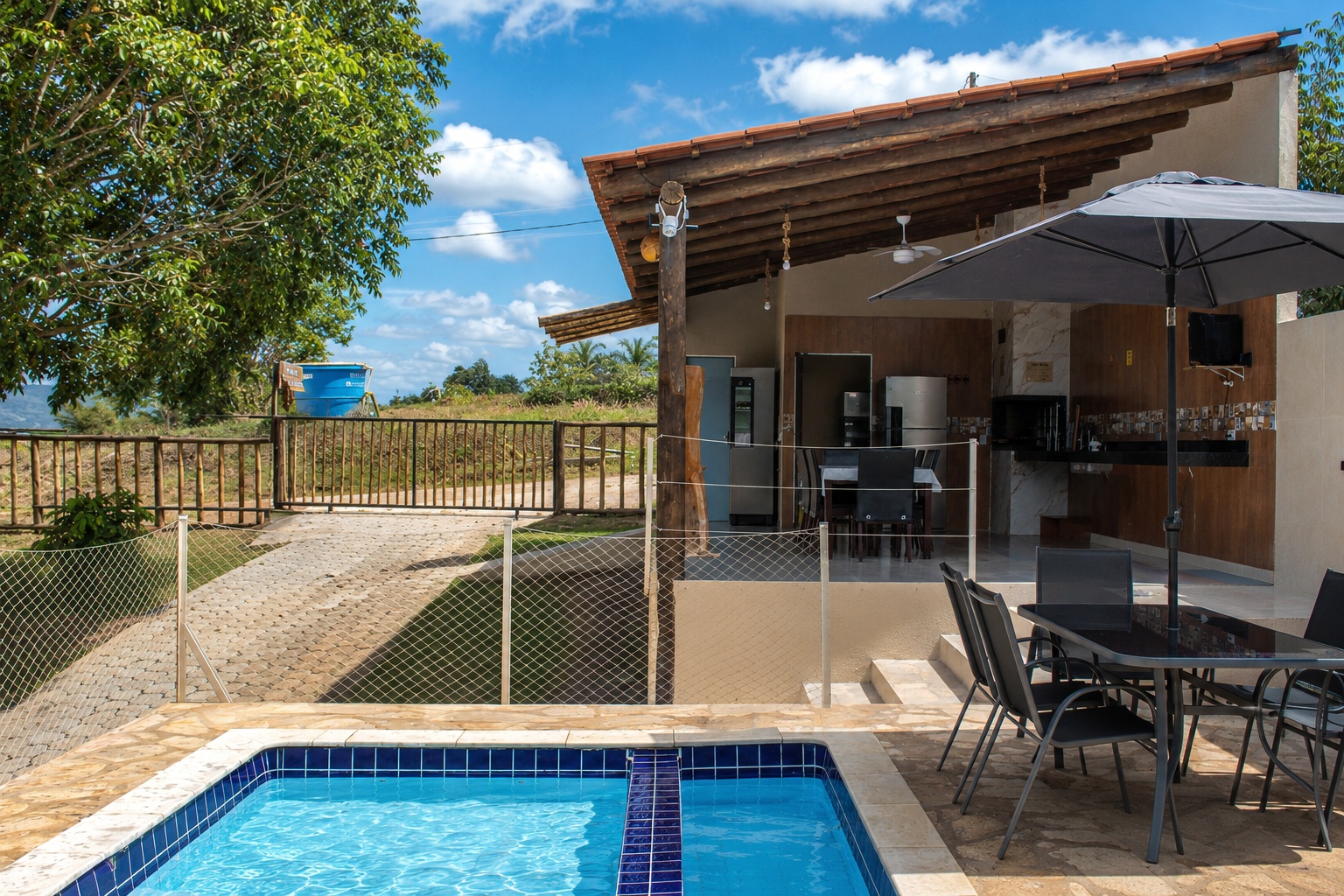 Piscina e área gourmet do Recanto dos Canários sob o céu azul